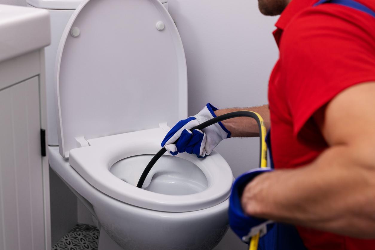 Plumber uses special tool to unclog toilet during drain cleaning service call